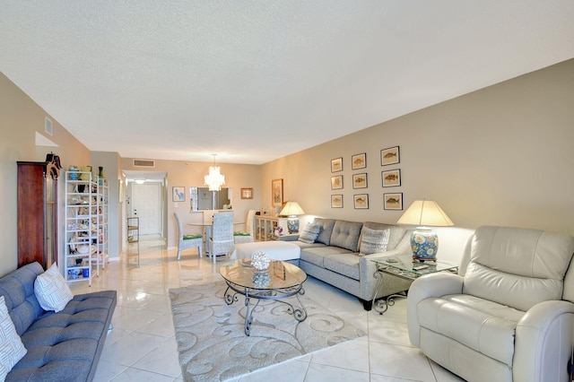 living room with a textured ceiling, a notable chandelier, and light tile patterned flooring