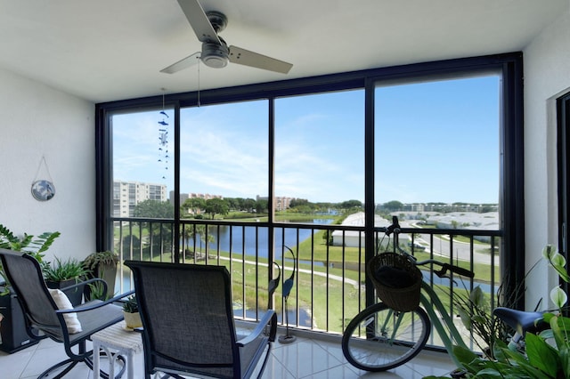 sunroom / solarium featuring ceiling fan and a water view