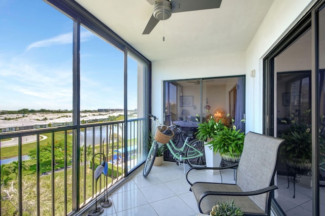 sunroom featuring ceiling fan and a water view