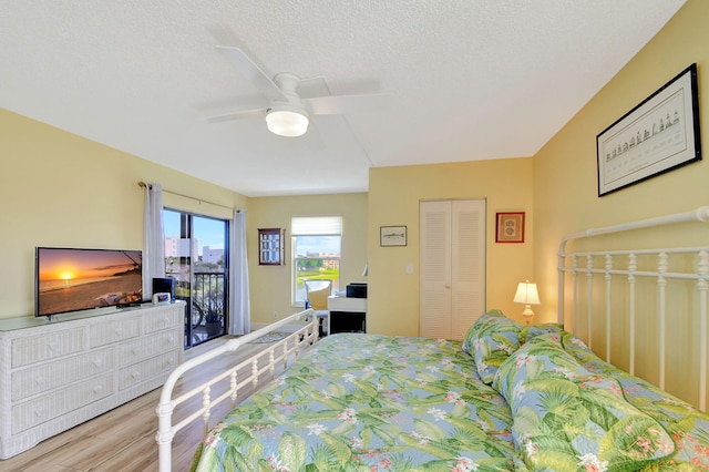 bedroom with a textured ceiling, access to outside, ceiling fan, hardwood / wood-style flooring, and a closet