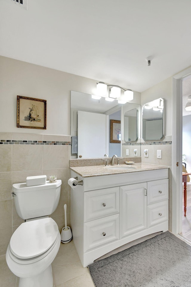 bathroom with tile patterned flooring, vanity, tile walls, and toilet