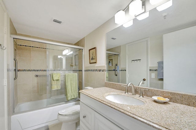 full bathroom with vanity, toilet, enclosed tub / shower combo, and tile walls