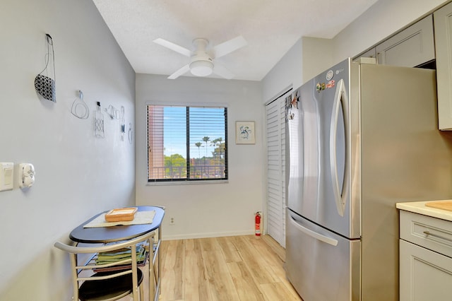 kitchen with gray cabinetry, ceiling fan, stainless steel fridge, and light wood-type flooring