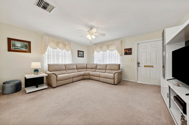 carpeted living room featuring a textured ceiling, ceiling fan, and a healthy amount of sunlight