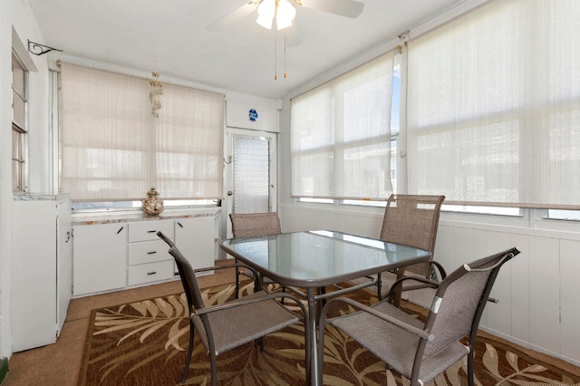 dining area with ceiling fan and wood walls