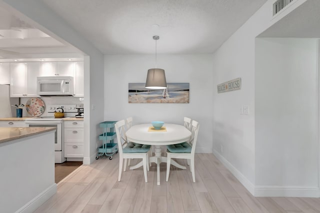 dining area with a textured ceiling and light hardwood / wood-style flooring