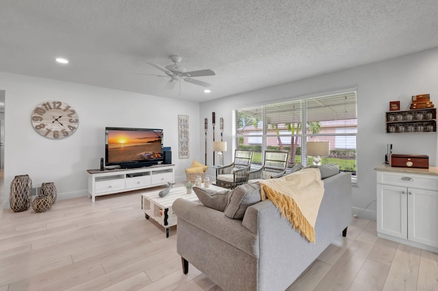 living room with a textured ceiling, light hardwood / wood-style floors, and ceiling fan