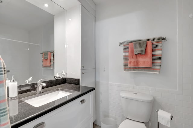 bathroom with vanity, tile walls, and toilet