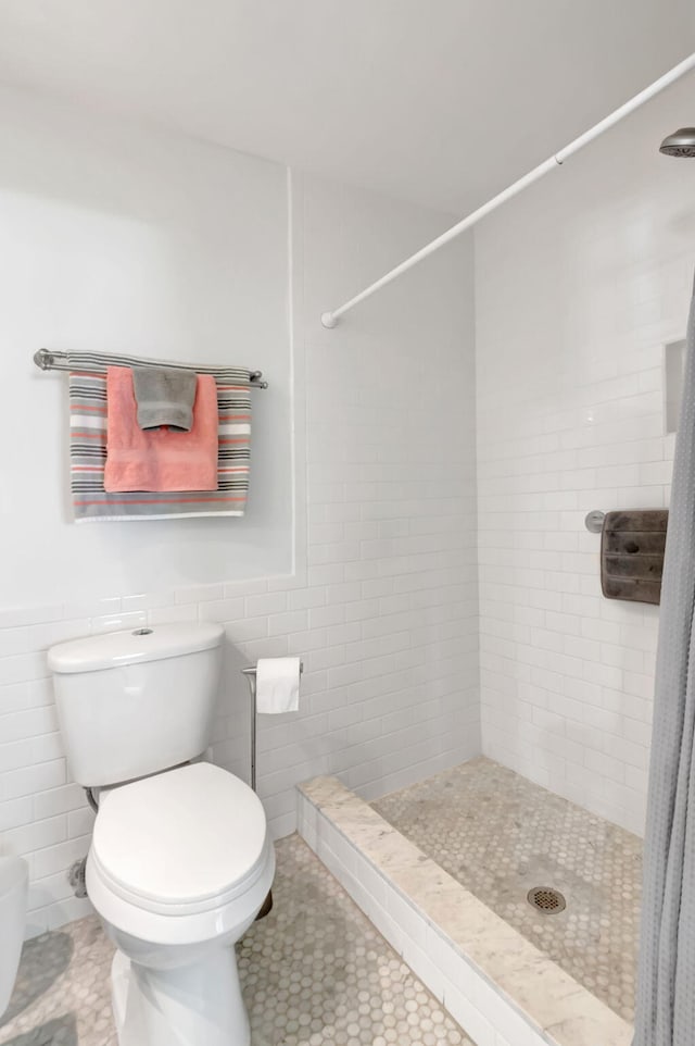 bathroom featuring toilet, tile patterned flooring, tile walls, and a shower with shower curtain