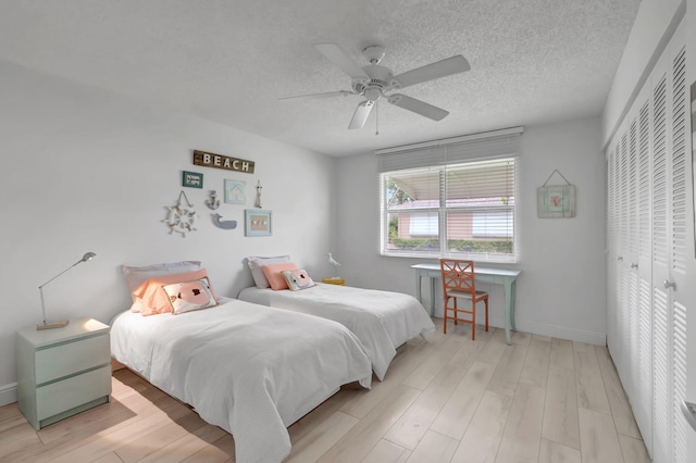 bedroom featuring a textured ceiling, light hardwood / wood-style flooring, a closet, and ceiling fan