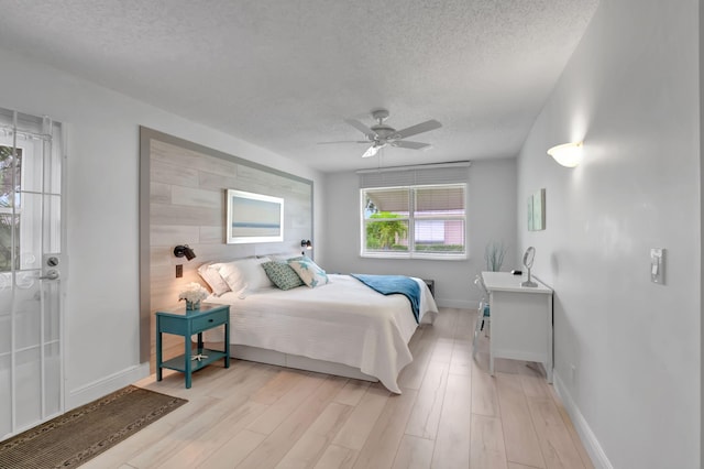 bedroom with ceiling fan, a textured ceiling, and light hardwood / wood-style flooring