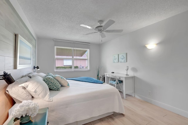 bedroom with ceiling fan, light wood-type flooring, and a textured ceiling