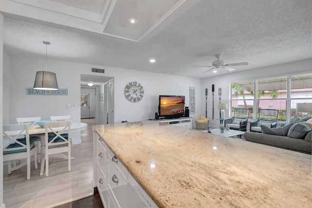 kitchen with ceiling fan, light stone countertops, hanging light fixtures, light hardwood / wood-style floors, and white cabinets