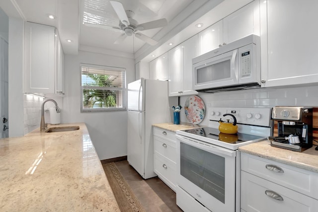 kitchen with light stone countertops, sink, white cabinets, and white appliances