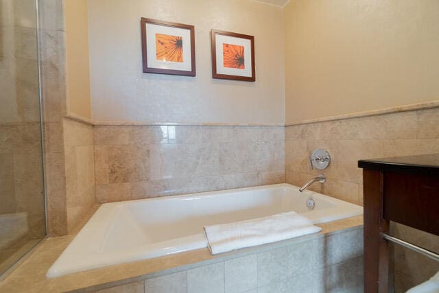 bathroom featuring tiled tub and vanity