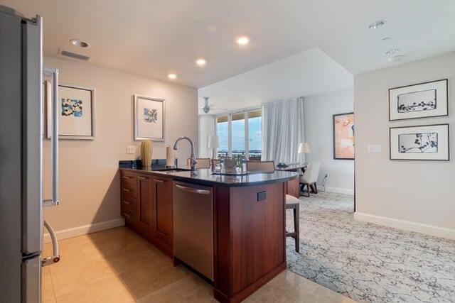 kitchen featuring kitchen peninsula, a kitchen bar, stainless steel appliances, ceiling fan, and sink