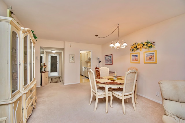 dining space featuring light carpet and an inviting chandelier