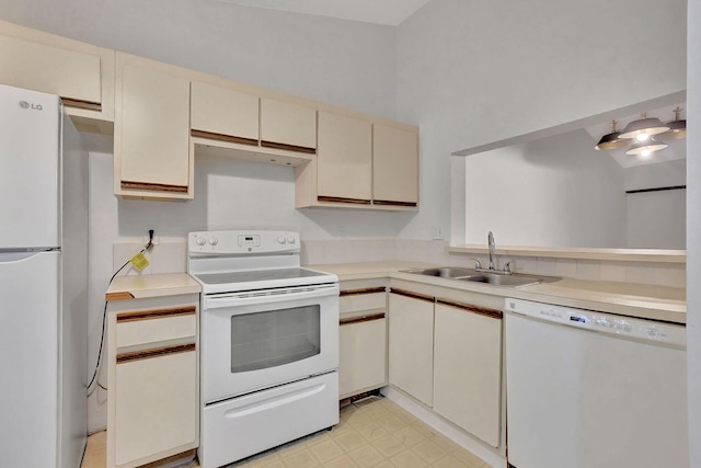 kitchen with sink, cream cabinets, and white appliances