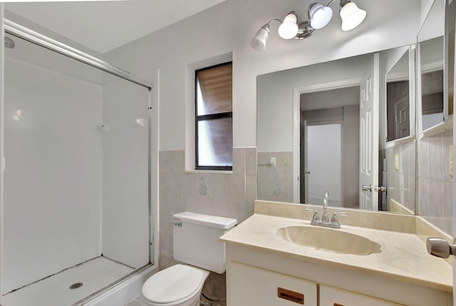 bathroom with toilet, vanity, a shower with shower door, and tile walls