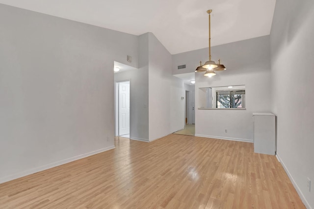 spare room with a towering ceiling and light hardwood / wood-style flooring