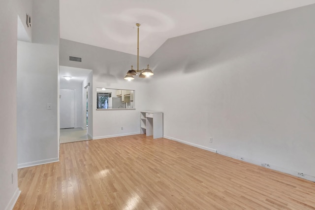 unfurnished living room featuring light hardwood / wood-style flooring, an inviting chandelier, and lofted ceiling