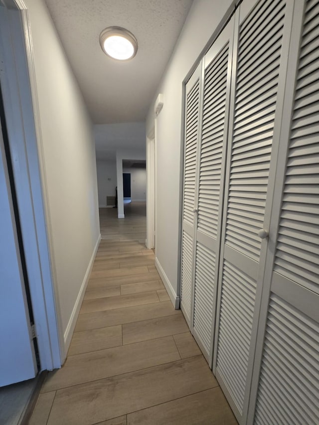 hallway featuring light hardwood / wood-style flooring and a textured ceiling