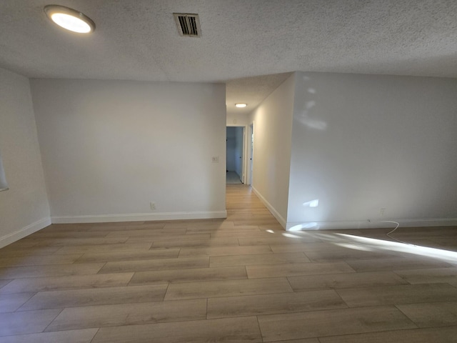 unfurnished room featuring a textured ceiling and light hardwood / wood-style flooring