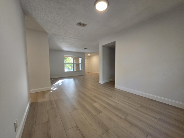 spare room with a textured ceiling and light hardwood / wood-style flooring