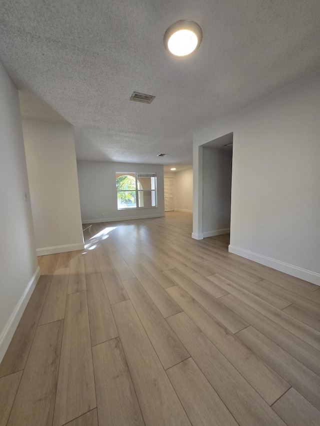 empty room with light hardwood / wood-style floors and a textured ceiling