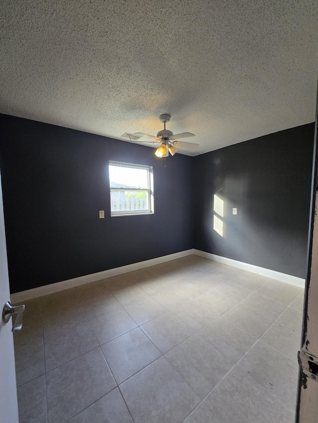 tiled empty room featuring ceiling fan and a textured ceiling