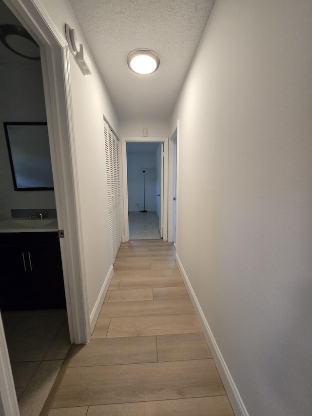 hallway featuring light wood-type flooring and a textured ceiling