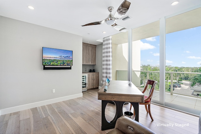 home office featuring floor to ceiling windows, light hardwood / wood-style floors, ceiling fan, and beverage cooler