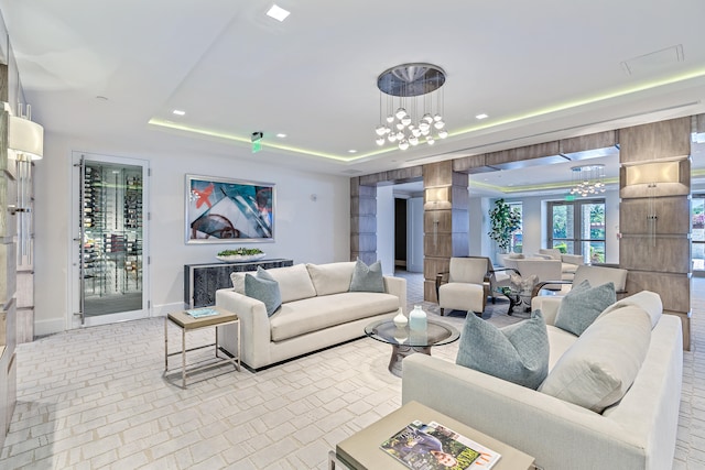 living room featuring french doors, an inviting chandelier, and a raised ceiling