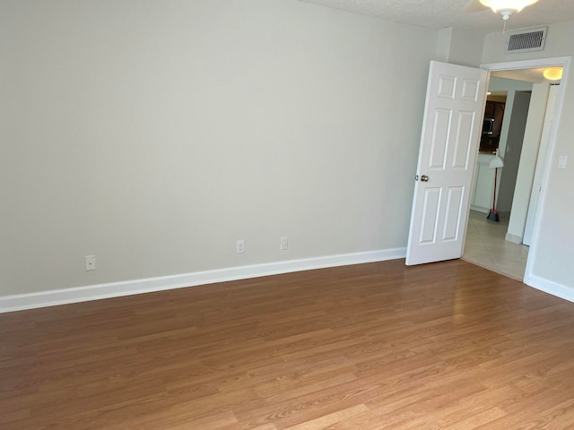 unfurnished room with light wood-type flooring and a textured ceiling