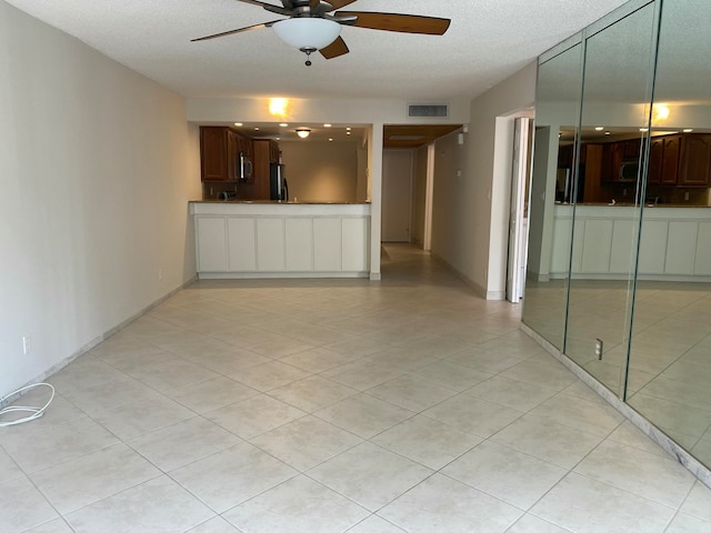 unfurnished living room featuring light tile patterned floors, a textured ceiling, and ceiling fan