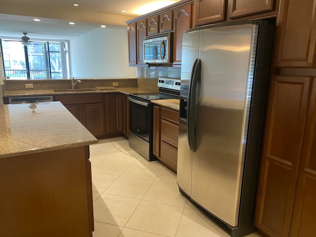 kitchen featuring sink, light tile patterned floors, light stone counters, kitchen peninsula, and stainless steel appliances