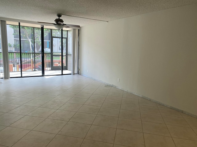 tiled spare room with a wealth of natural light, a textured ceiling, expansive windows, and ceiling fan