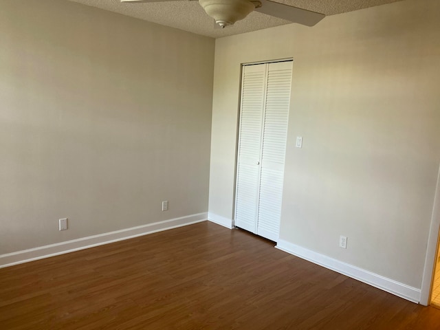 unfurnished bedroom with ceiling fan, a closet, dark hardwood / wood-style floors, and a textured ceiling