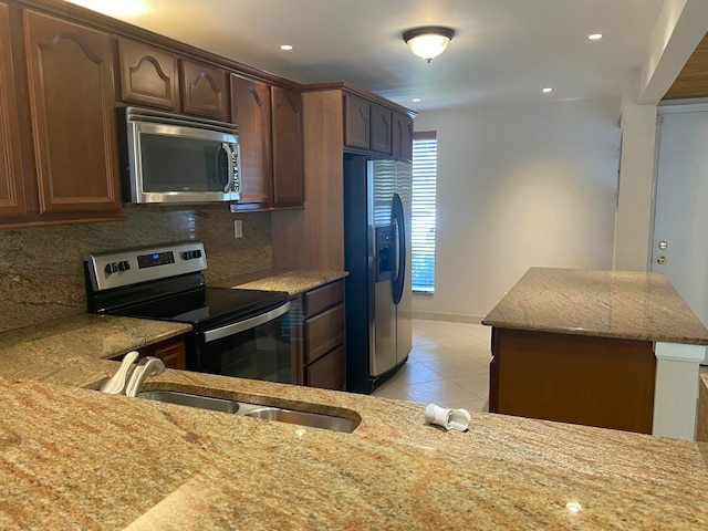 kitchen with decorative backsplash, appliances with stainless steel finishes, light stone counters, sink, and light tile patterned flooring