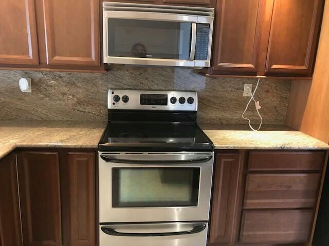 kitchen with light stone countertops, backsplash, and stainless steel appliances