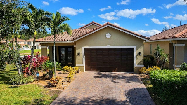 mediterranean / spanish home featuring an attached garage, a tiled roof, decorative driveway, and stucco siding