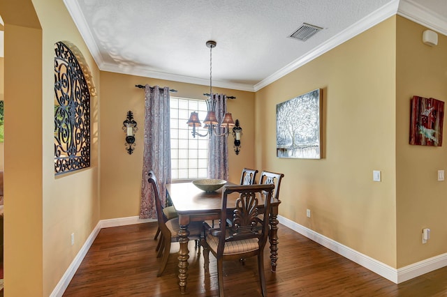 dining room with a textured ceiling, dark hardwood / wood-style flooring, crown molding, and an inviting chandelier