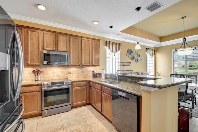 kitchen with pendant lighting, sink, appliances with stainless steel finishes, a tray ceiling, and kitchen peninsula