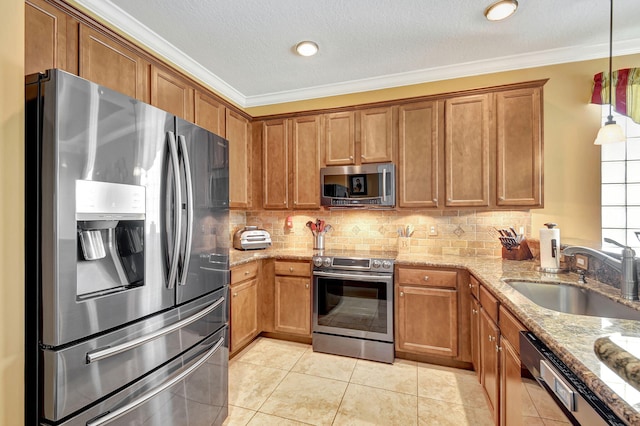 kitchen with sink, light stone counters, pendant lighting, light tile patterned flooring, and appliances with stainless steel finishes