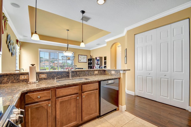 kitchen featuring stainless steel dishwasher, sink, hanging light fixtures, and a tray ceiling