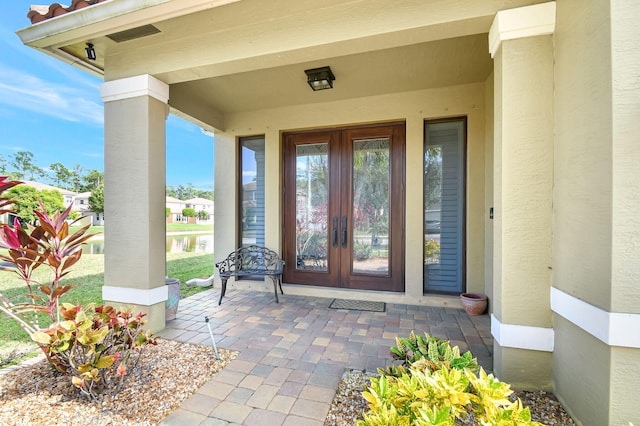 view of exterior entry featuring french doors and stucco siding