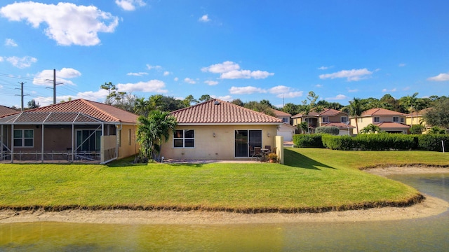 rear view of house with a lanai, a lawn, and a water view