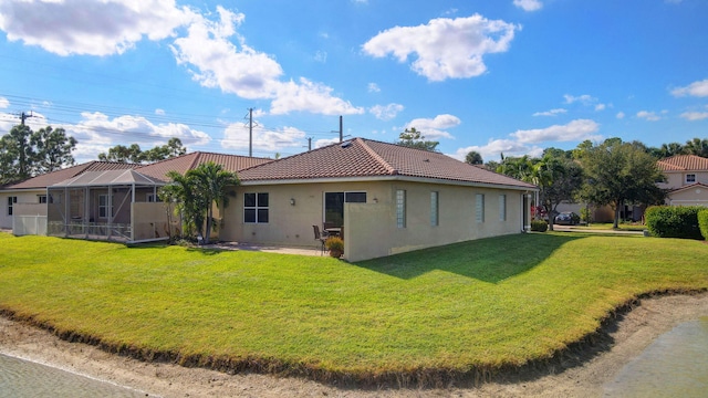 back of house featuring a lawn, glass enclosure, and a patio area