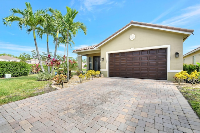 view of front of house featuring a garage, stucco siding, a tile roof, decorative driveway, and a front yard