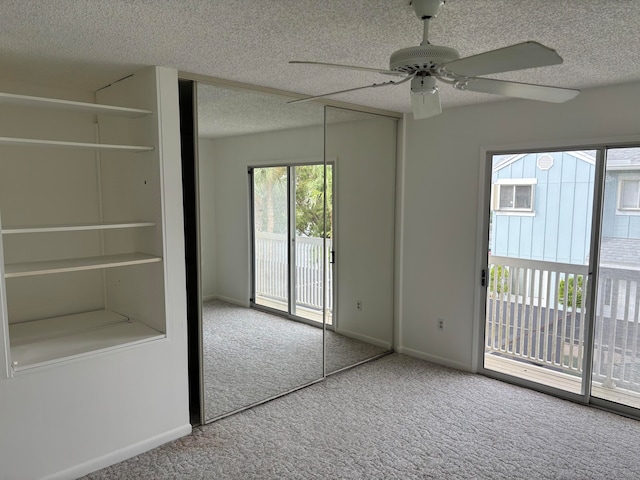 unfurnished bedroom with access to outside, ceiling fan, carpet, and a textured ceiling